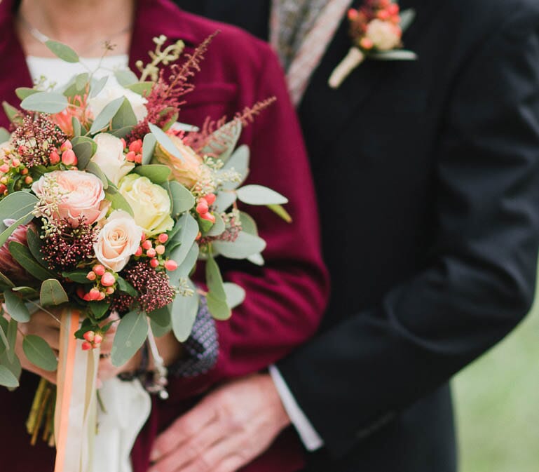 DIY wedding flowers for fall, featuring a bouquet and floral crown with coral garden roses, scabiosa pods, olive leaf, waxflower and chrysanthemums.