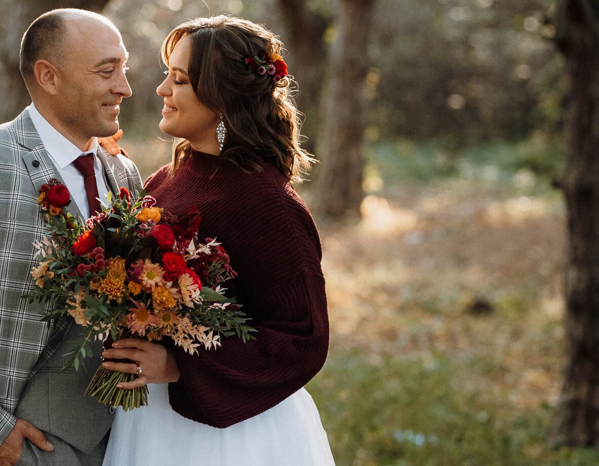 DIY autumn wedding bouquet with golden football mums, red carnations, bronze mums, and red button pompons.