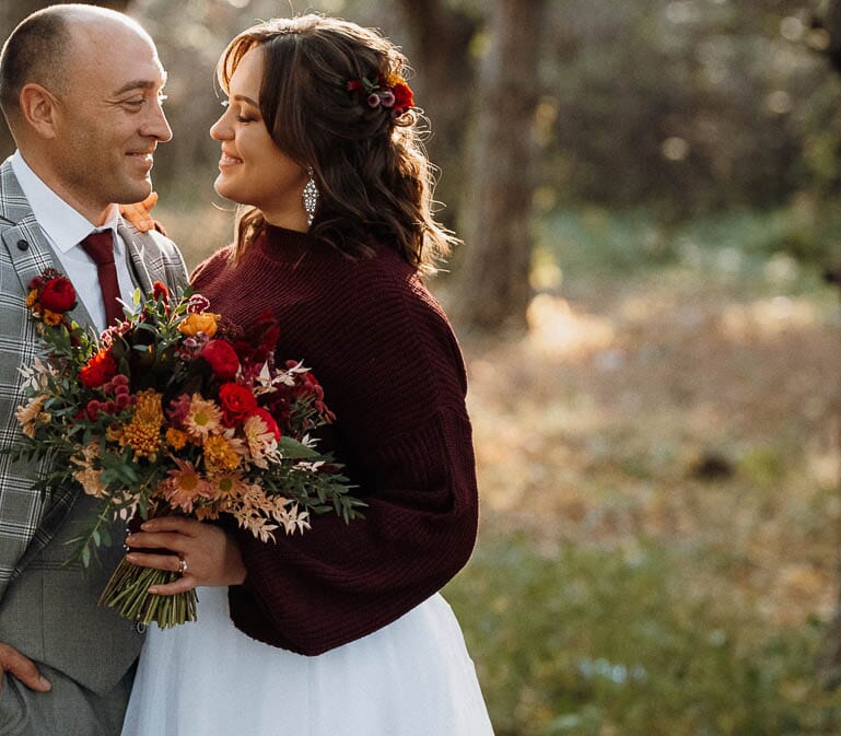 DIY autumn wedding bouquet with golden football mums, red carnations, bronze mums, and red button pompons.