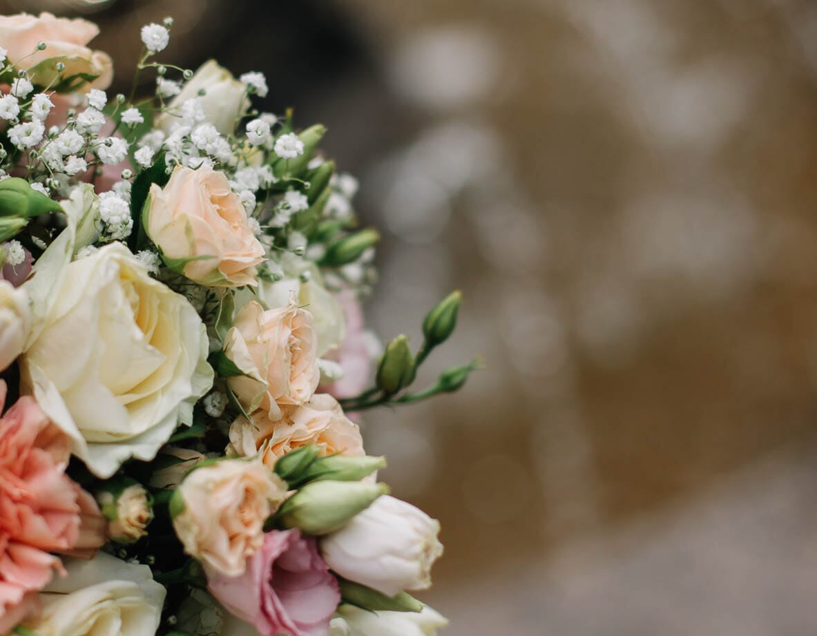 DIY bridal bouquet with peach spray roses, white roses, peach carnations, and baby's breath