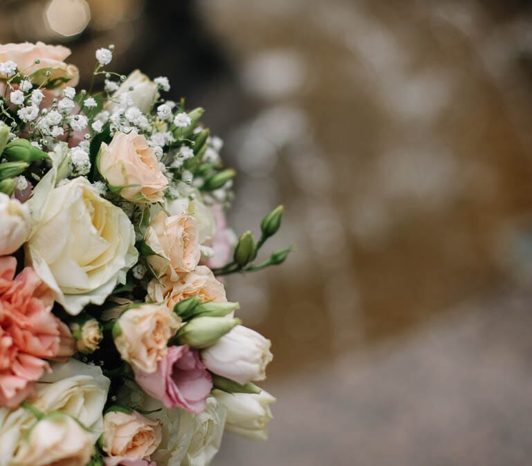 DIY bridal bouquet with peach spray roses, white roses, peach carnations, and baby's breath