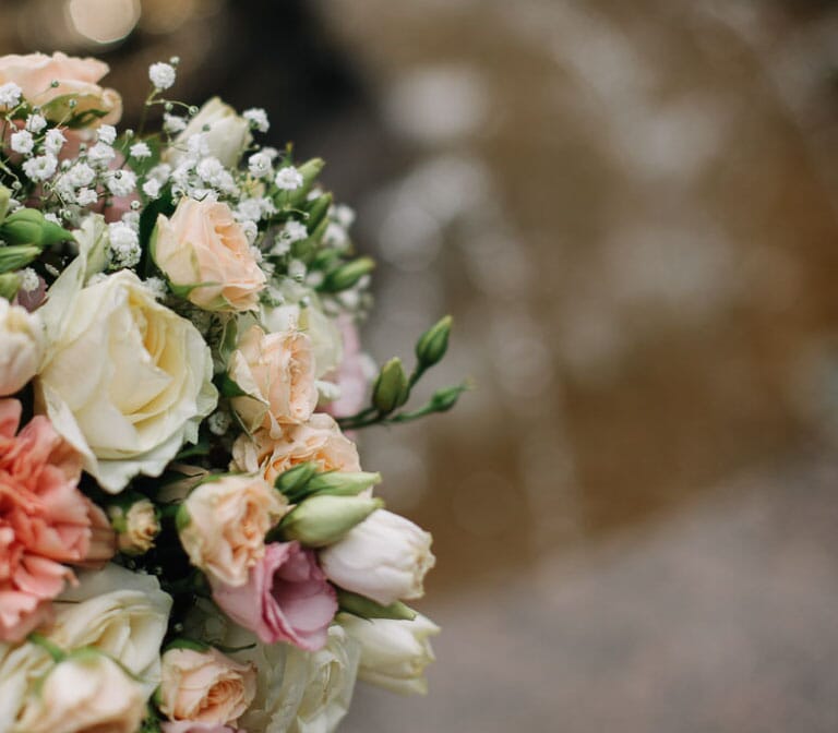 DIY bridal bouquet with peach spray roses, white roses, peach carnations, and baby's breath